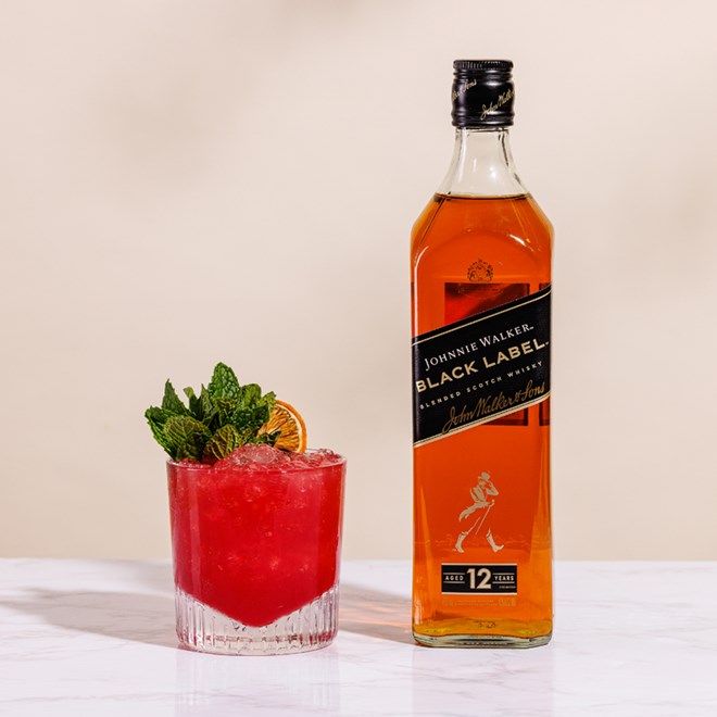 A Cherry Whiskey Smash Cocktail next to a Johnnie Walker Black Label whiskey bottle